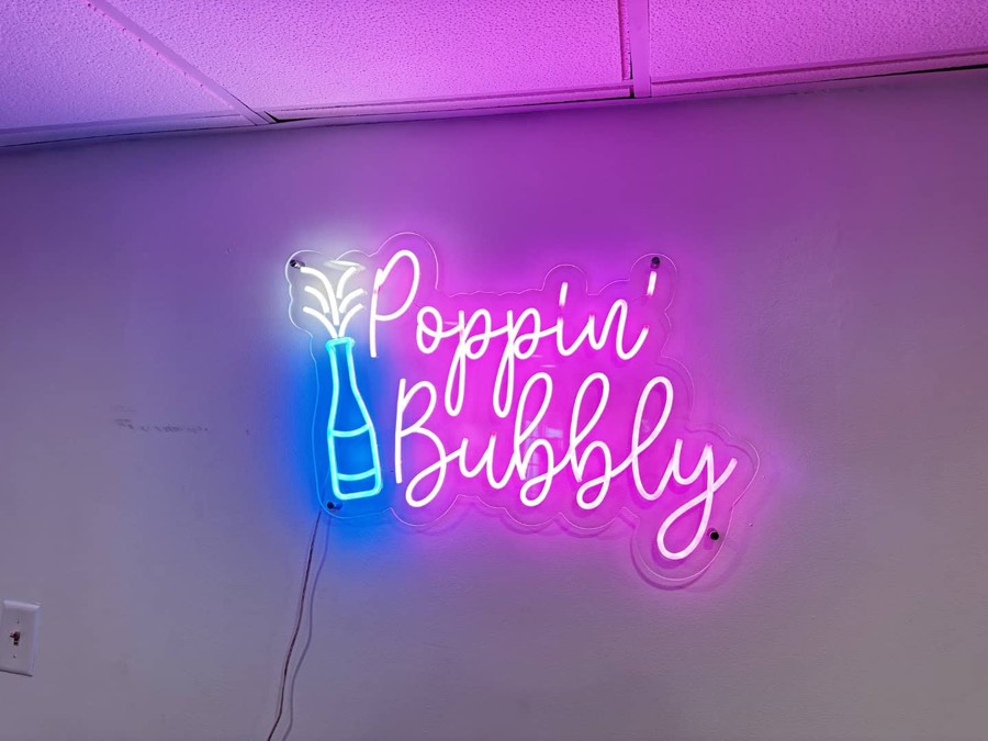Neon sign reading Poppin' Bubbly with a champagne bottle